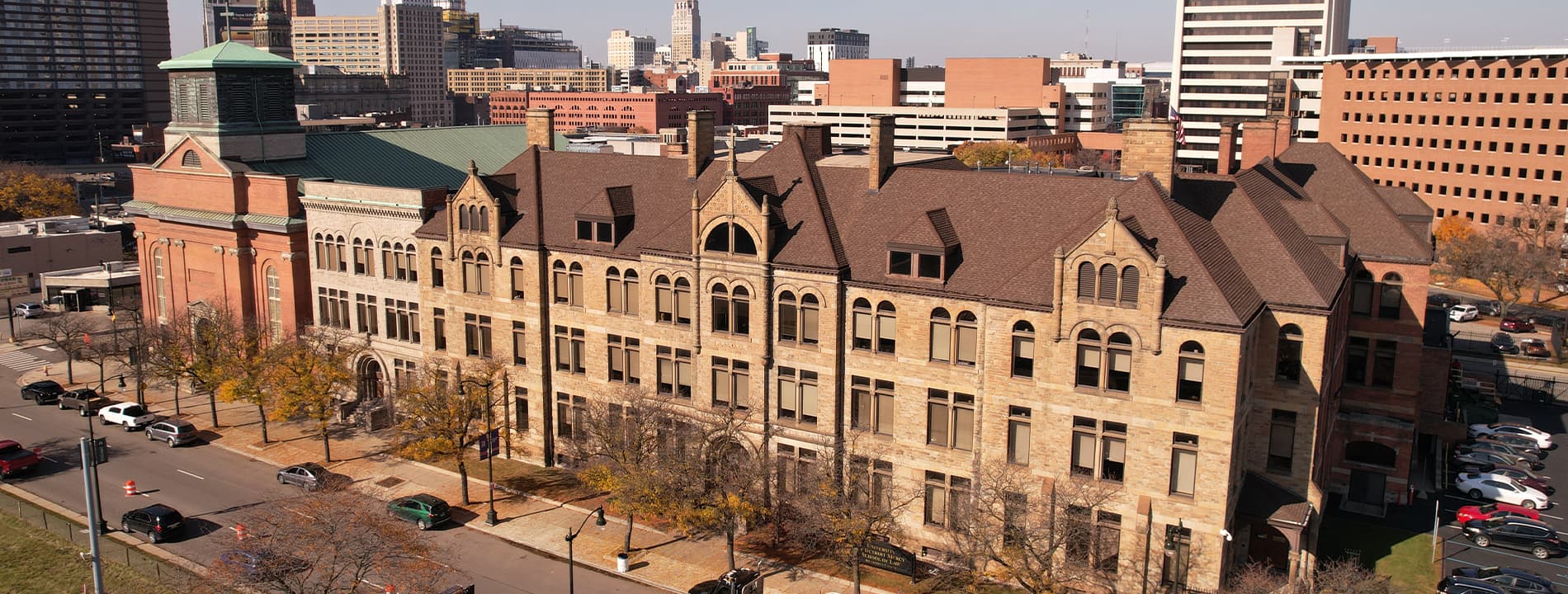 An aerial photo of Detroit Mercy's School of Law in downtown Detroit with other buildings and cars featured on a sunny day.